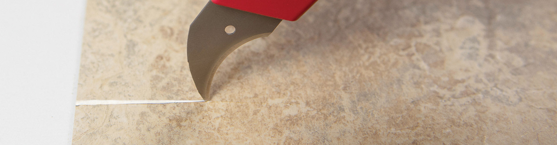 A ROBERTS Hawk Utility Blade in-use, cutting flooring material