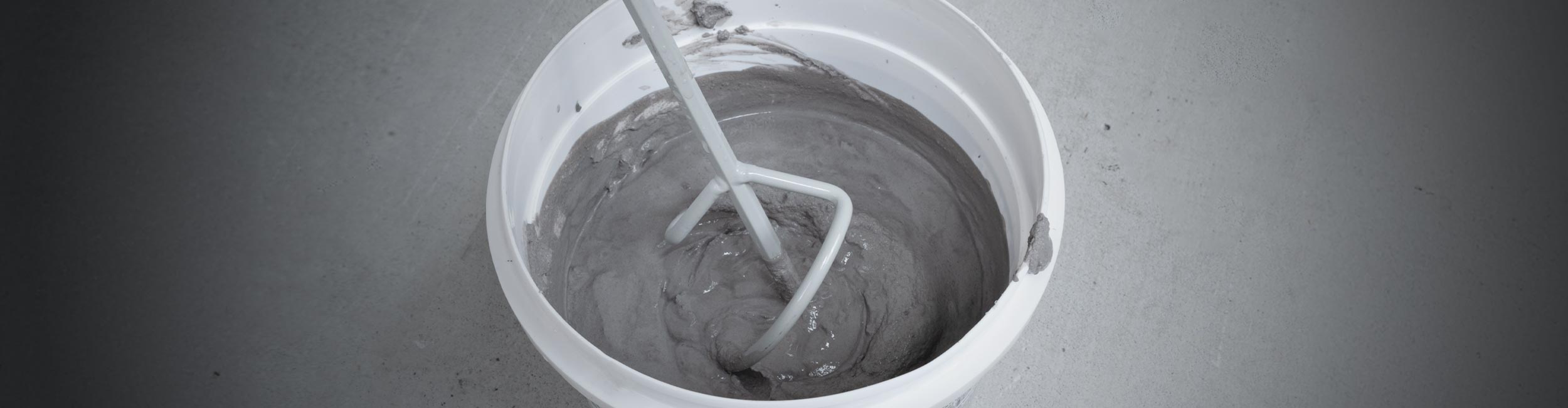 Close up of QEP's 16 in. Universal Mixing Paddle in a bucket with thinset