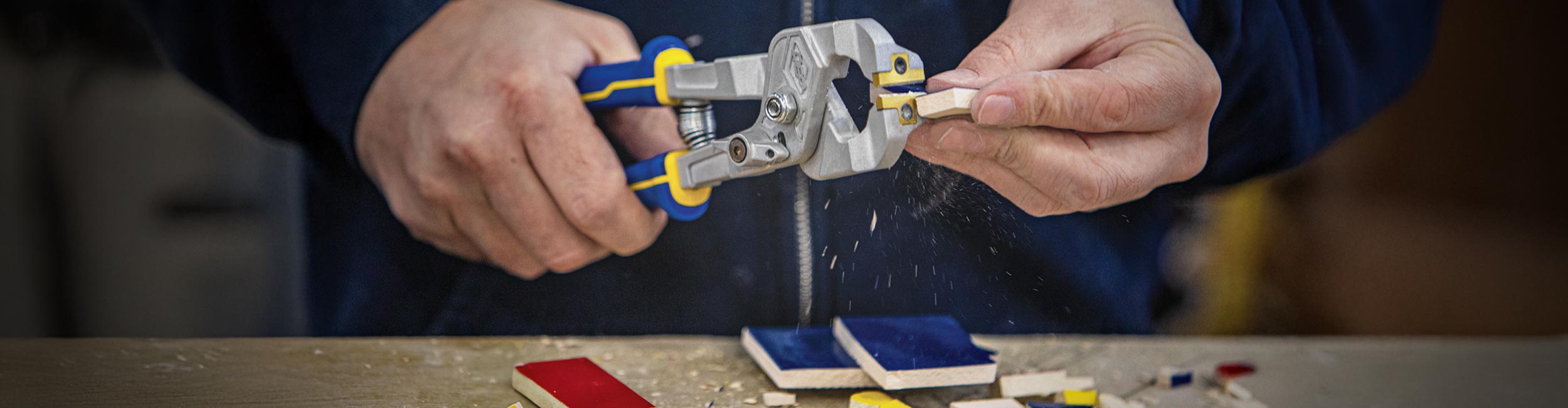 Close-up of hands using QEP's Artisan Power Nipper to precisely cut small mosaic pieces