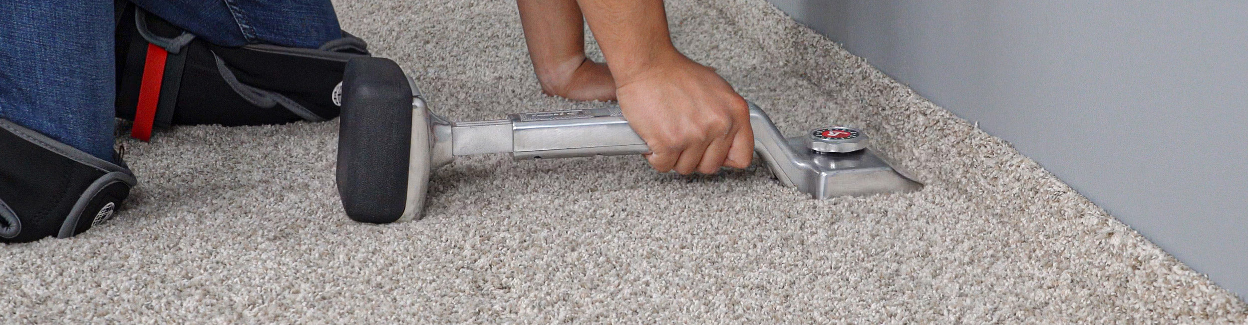 An installer using a ROBERTS knee kicker to stretch and secure carpet during installation