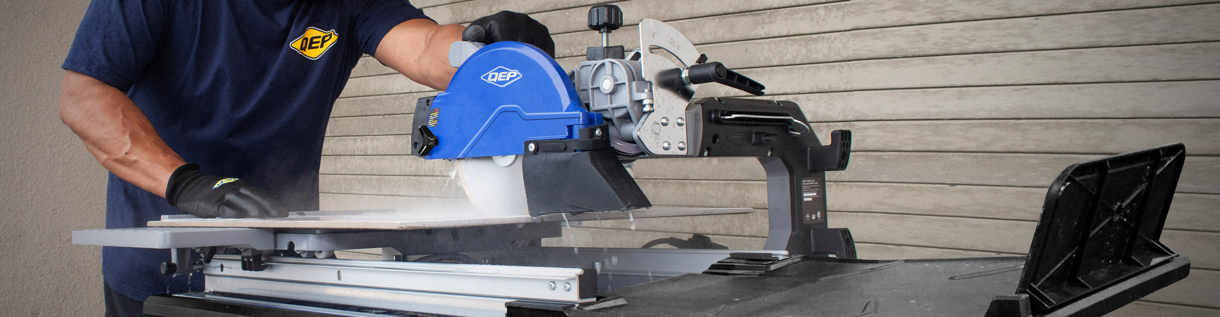 A professional installer wet cutting a large format tile with a QEP RC24 Overhead Tile Saw