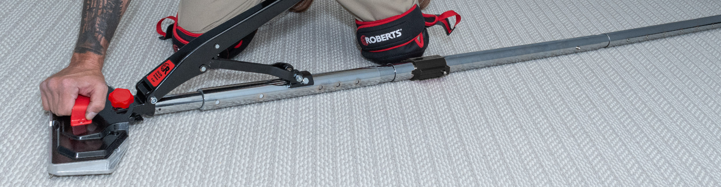A professional installer using the ROBERTS Falcon™ Power 44 Stretcher to stretch and secure carpet during installation