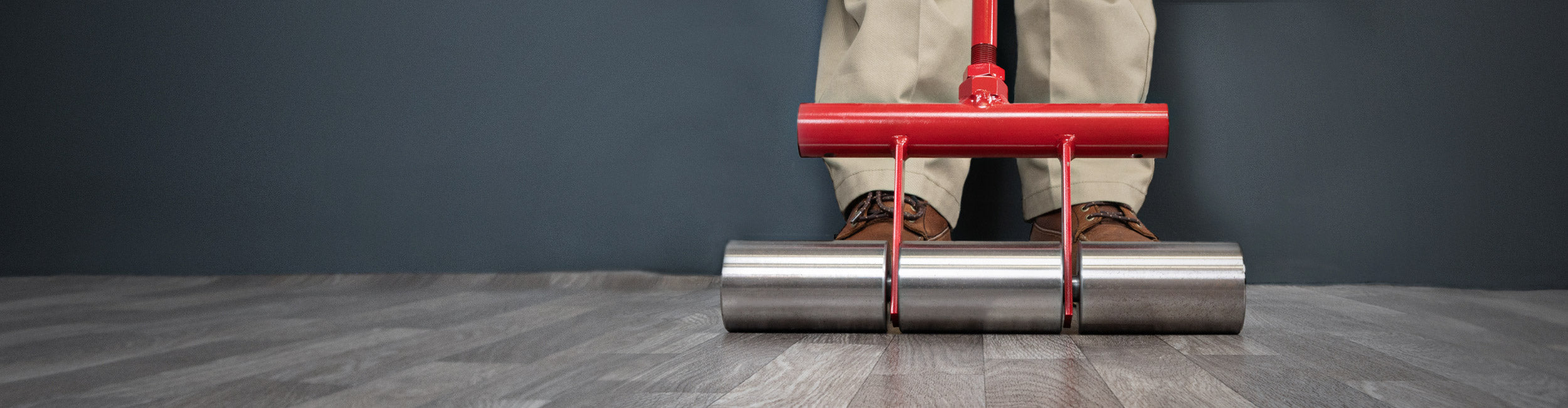 Close-up of an installer pressing sheet vinyl with a ROBERTS Heavy-duty Flooring Roller during installation