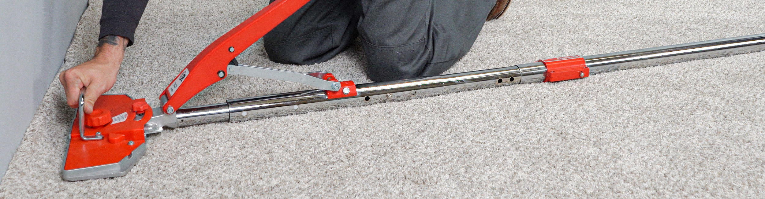 A professional installer using a ROBERTS Power-Lok Carpet Stretcher to stretch and secure carpet
