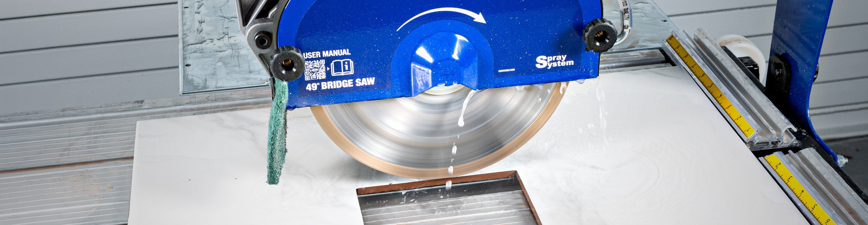 Close-up of QEP's 49" Bridge Saw and its water spray system cutting porcelain tile