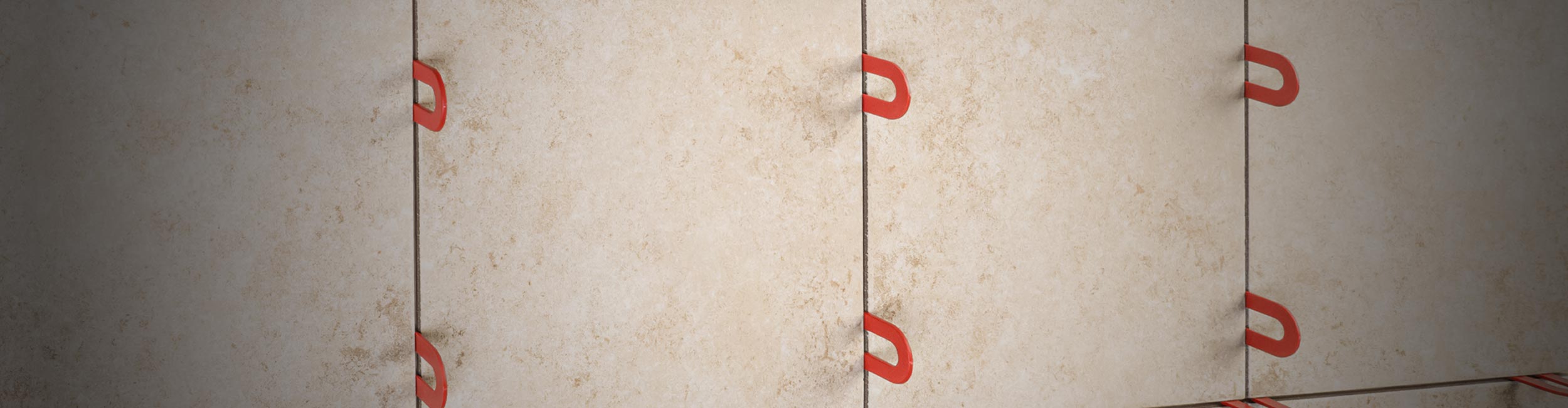 Close-up of tile installation with red QEP 1/8 in. Horseshoe Shims for even spacing and alignment