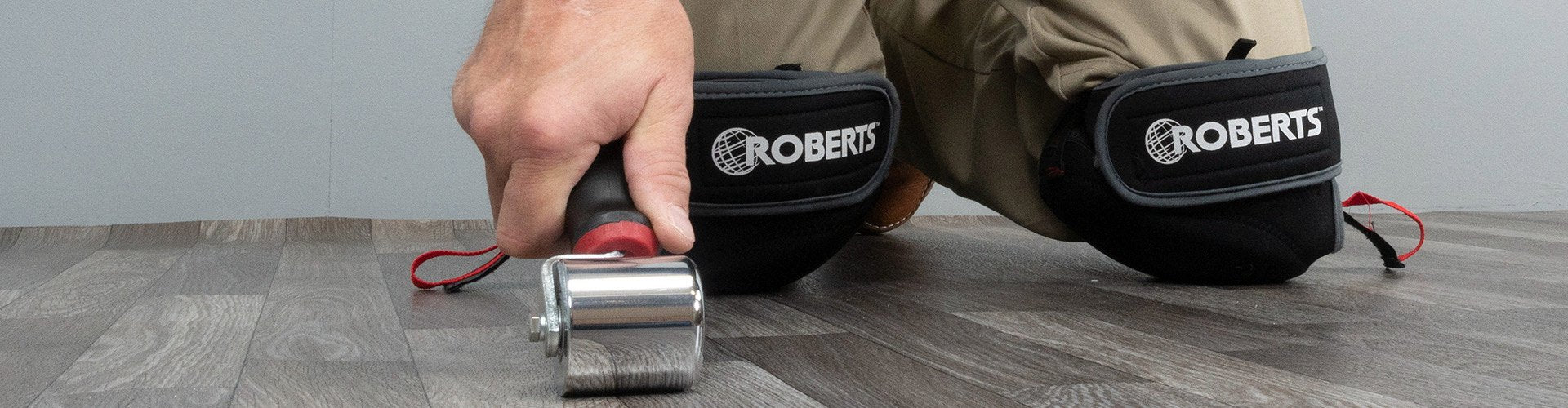Flooring installer using the ROBERTS Vinyl Seam Roller while wearing ROBERTS knee pads
