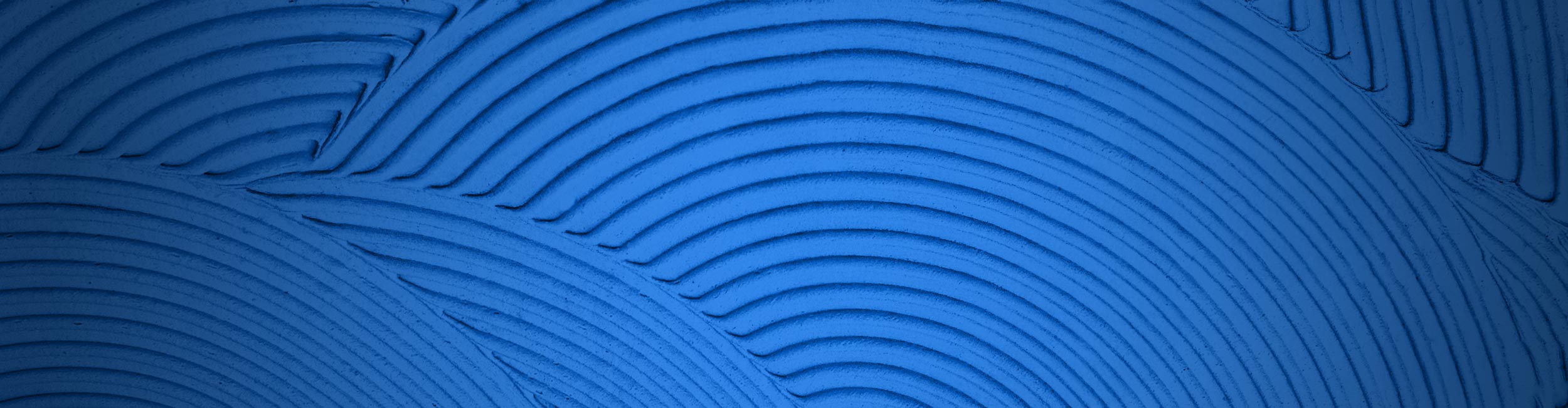 Close-up of textured trowel ridges with circular patterns on a blue background