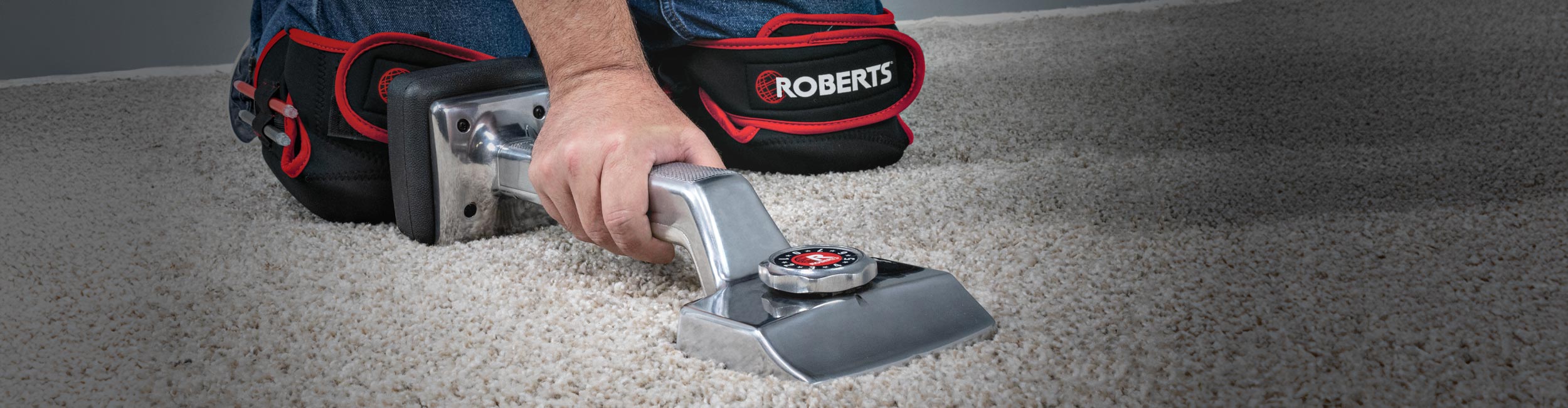 Close-up of an installer using ROBERTS THE GENERAL Knee Kicker to stretch carpet during installation