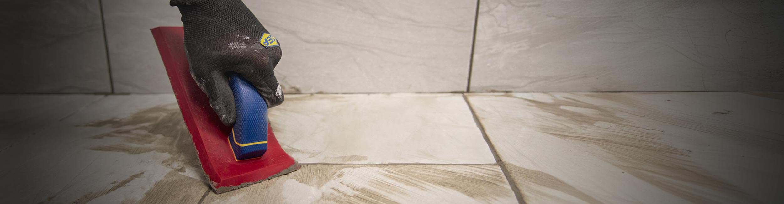 Close up of installer using QEP's Xtreme Stone Grout Float to evenly apply grout between tile joints