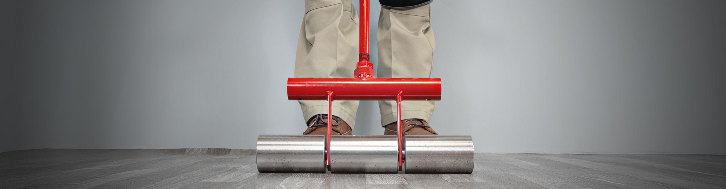 Close-up of installer using ROBERTS 35 lb. Heavy-Duty Flooring Roller to press out sheet vinyl