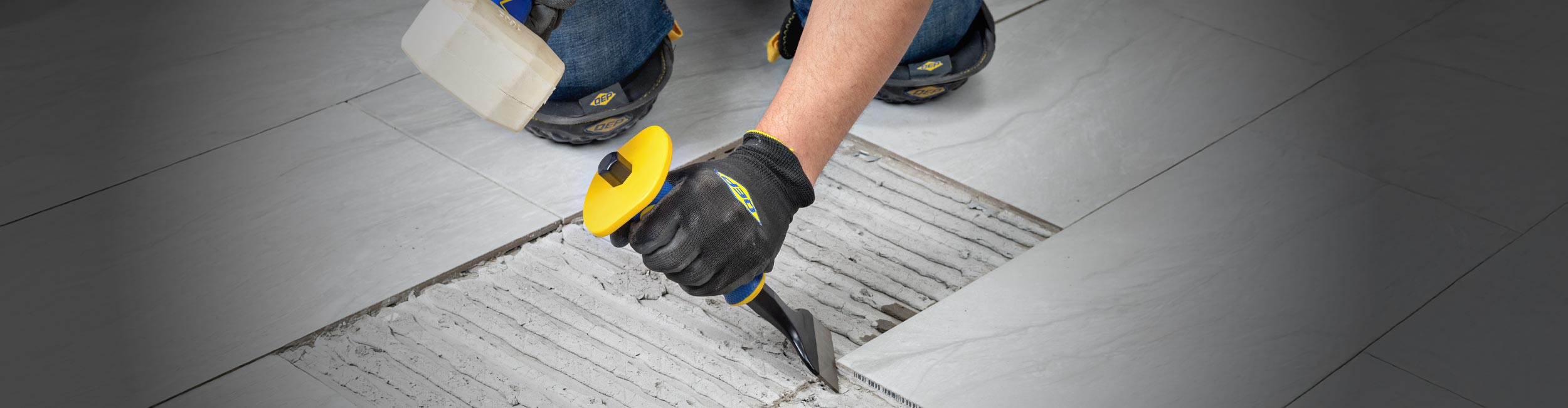 Close-up of installer using QEP's Xtreme Heavy Duty Chisel Scraper to remove old tile flooring