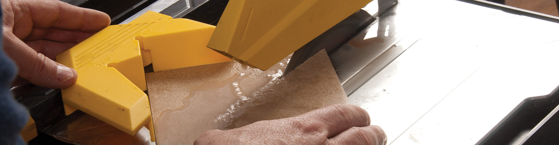 A tile installer cuts a tile with a QEP 700XT - 7 inch Wet Tile Saw