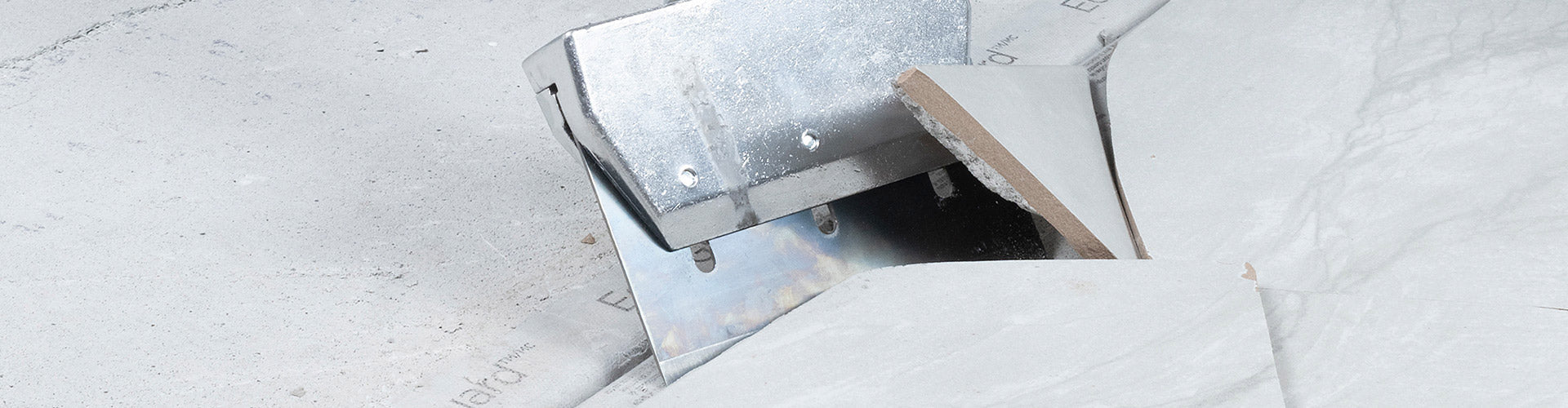 Close-up of a scraper blade being used to tear out old floor tile