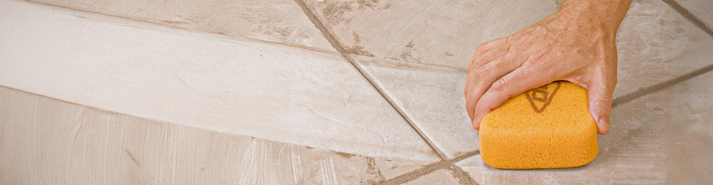 Close up of hand using QEP's Sponge to clean up grout residue after a tile installation