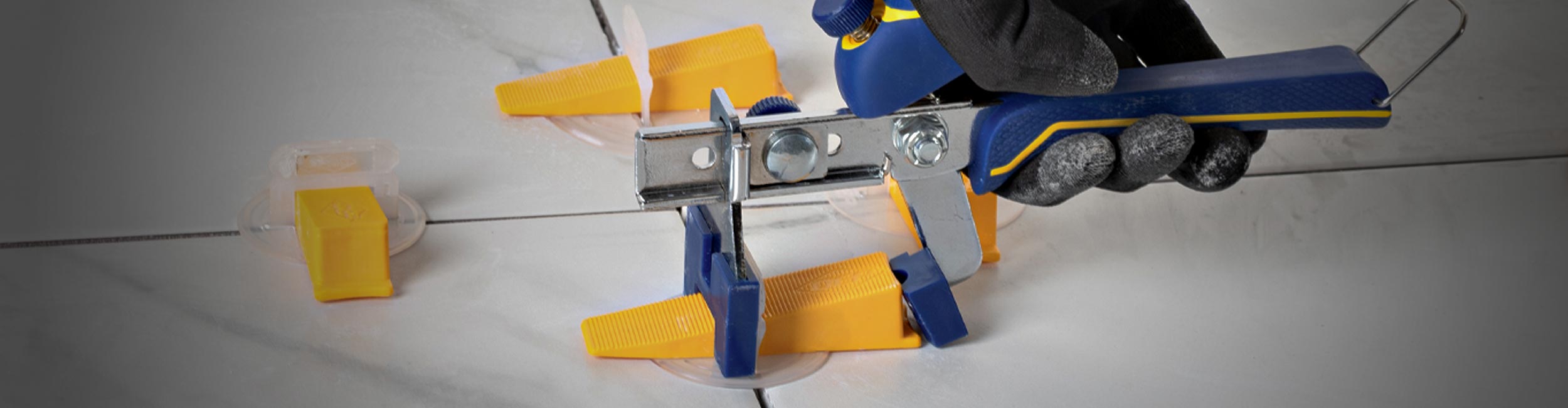 Installer using QEP's Pro Installation Pliers to tighten the LASH XL Tile Leveling System