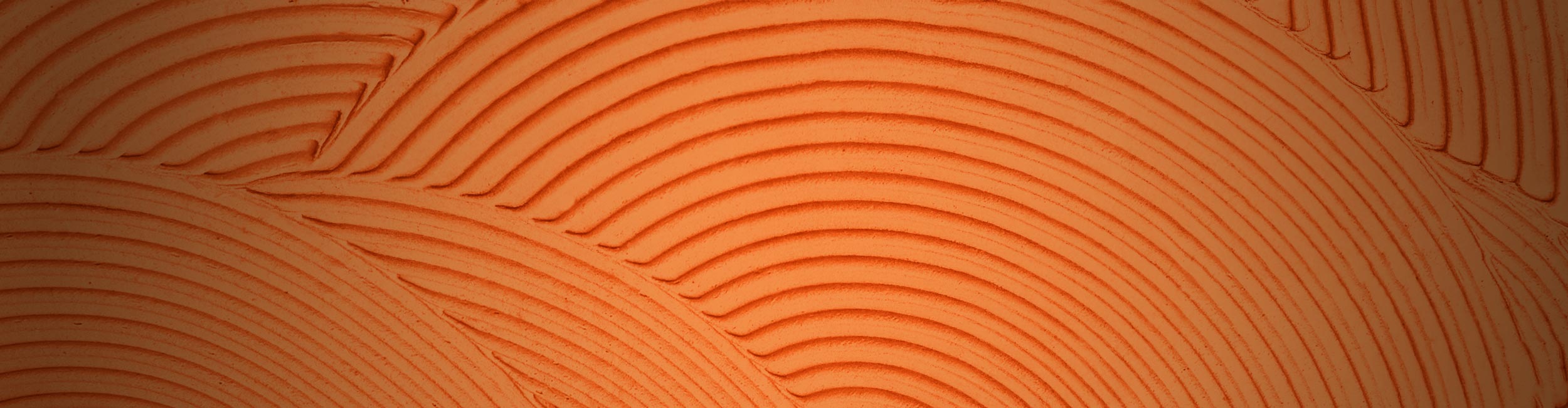 Close-up of textured trowel ridges with circular patterns on an orange background