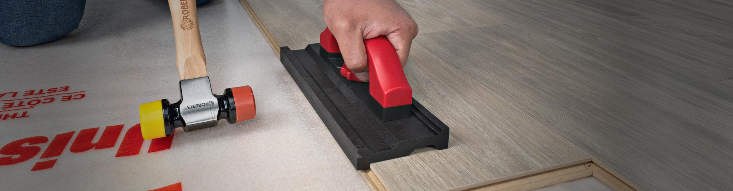 Installer using ROBERTS Double Tap Reversible Tapping Block to push flooring planks together