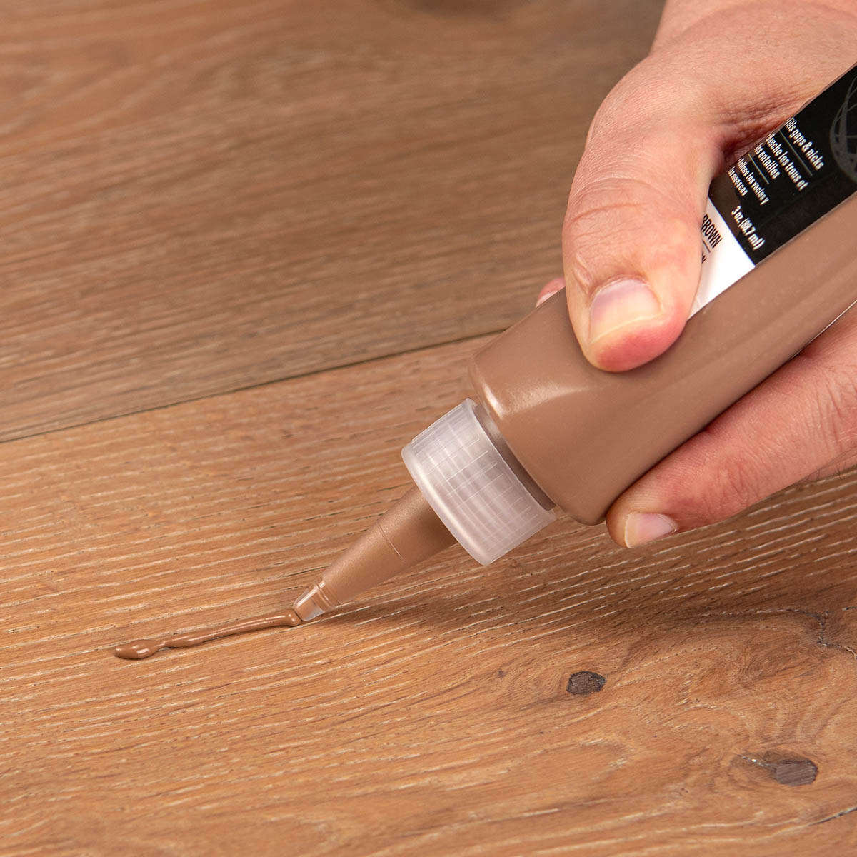 ROBERTS Floor Repair Putty being used to repair a brown wood floor
