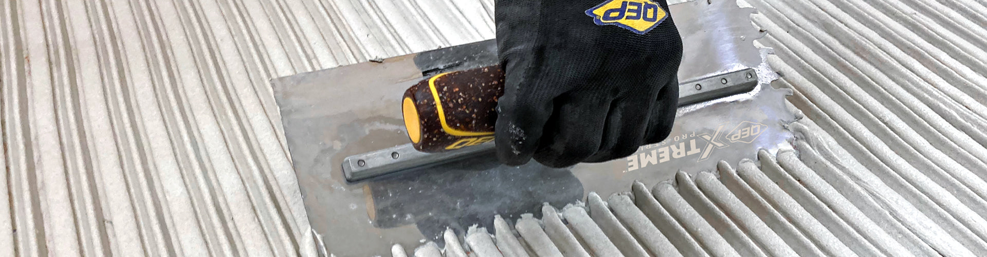 Close-up of a professional installer spreading thinset using a QEP Xtreme Euro Notch trowel